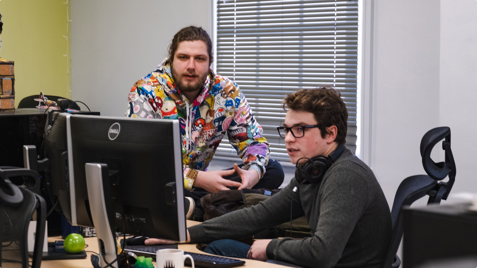 Photo of two Stainless Games employees working at a computer